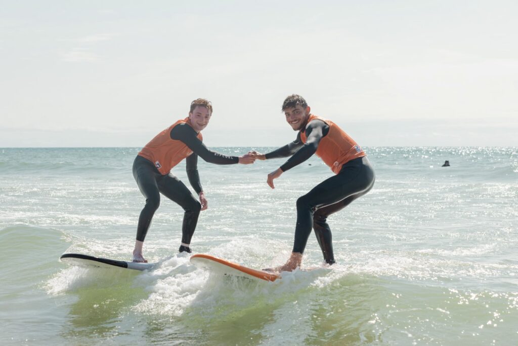 deux apprentis surfeurs à Lacanau se tiennent par la main