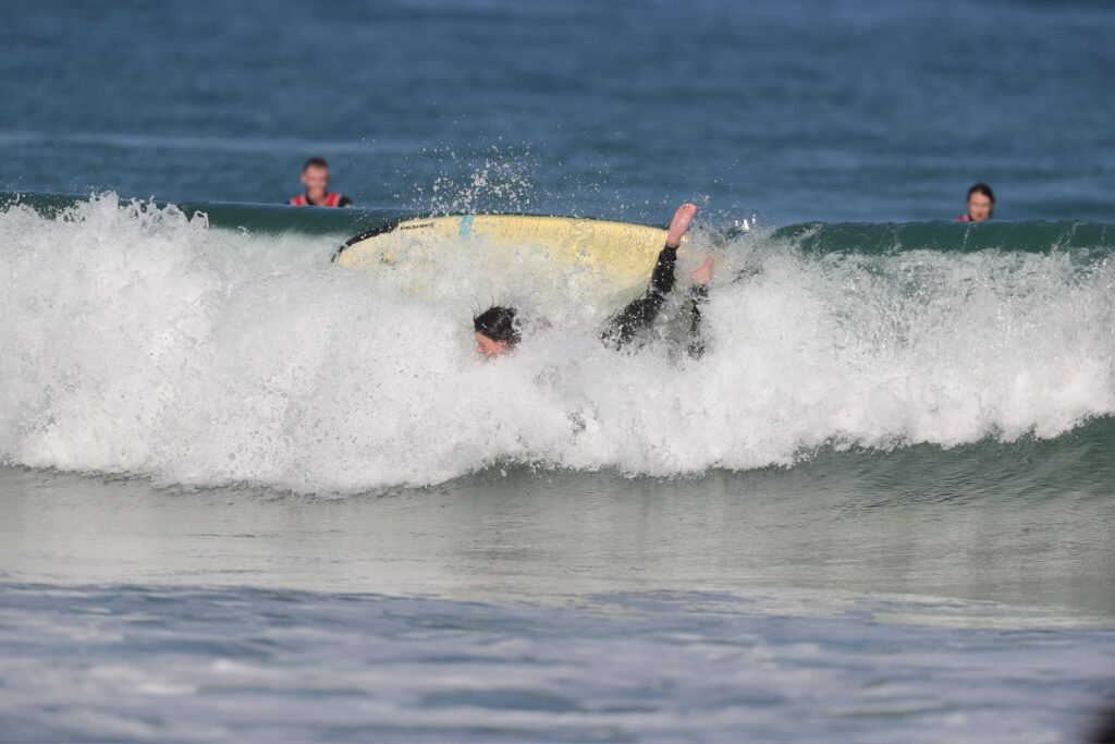 un apprenti surfeur chute de sa planche dans l'eau